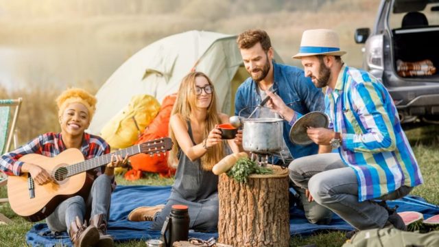 Friends spending time on outdoor recreation activities cooking and playing guitar
